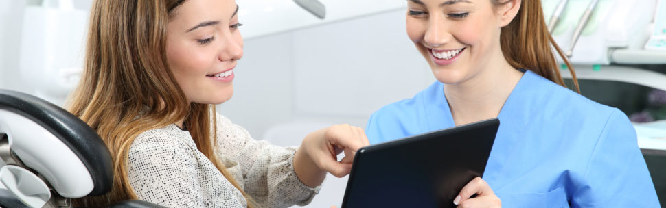 Dentist and patient choosing treatment Dentist and patient choosing treatment in a consultation with medical equipment in the background